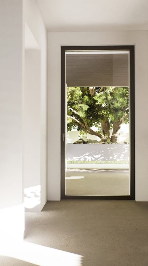 Porta finestra con telaio minimale in alluminio, che illumina una stanza moderna con una vista sul giardino.